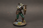 Miniature figurine of a warrior with armor and shield on a dark gray background
